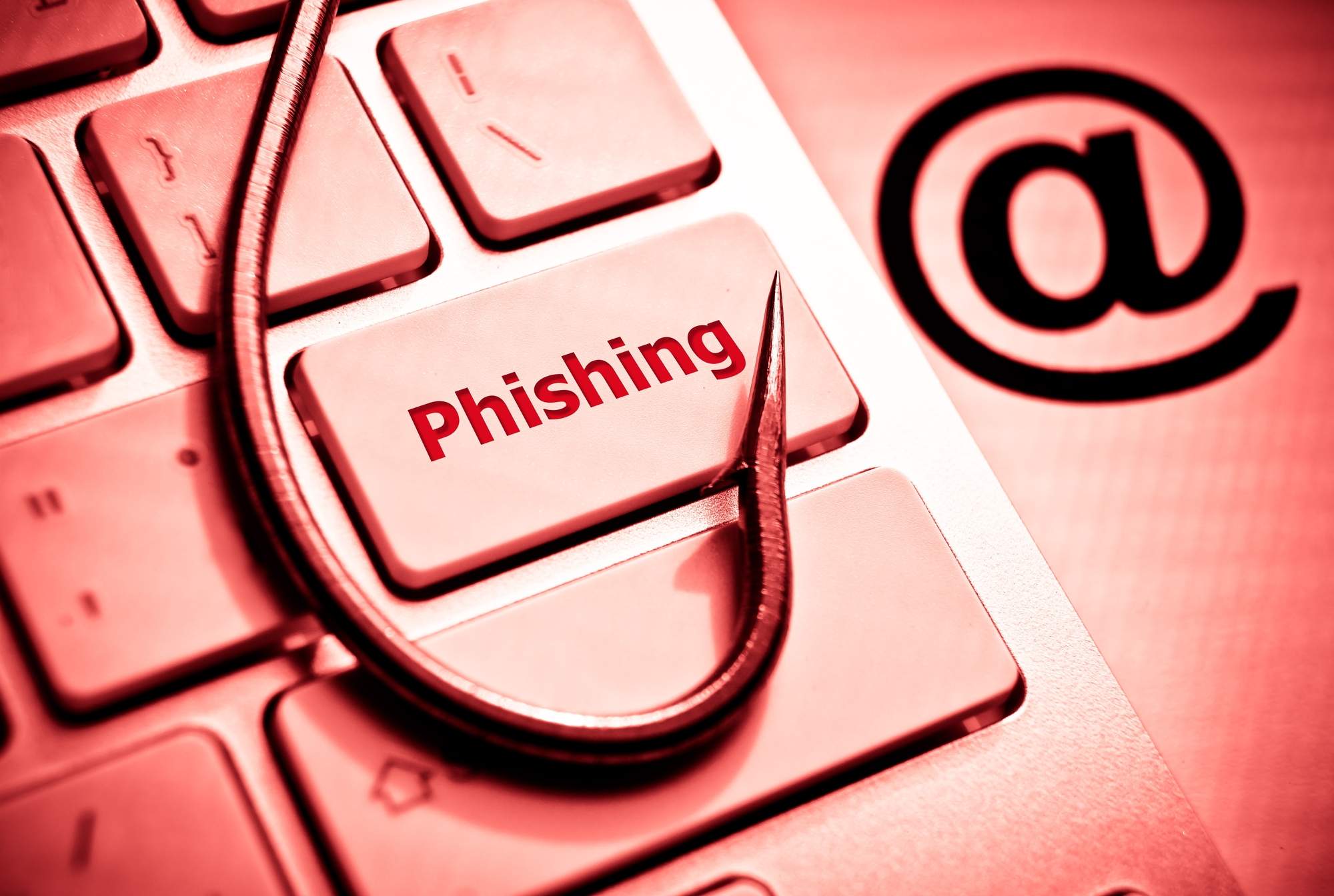 Phishing button with fishing hook on red-lit keyboard
